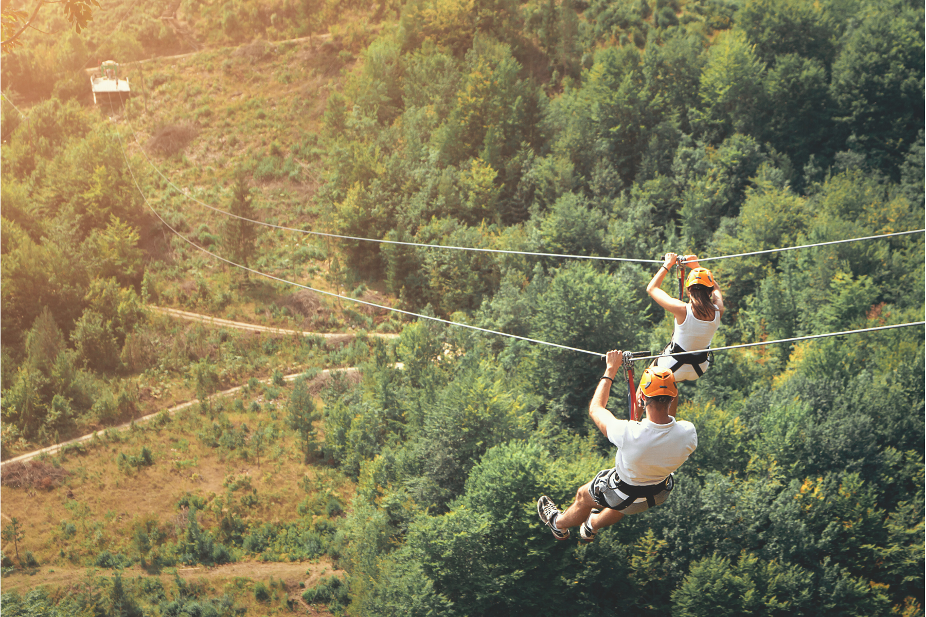 Couple zip-lining over a farm